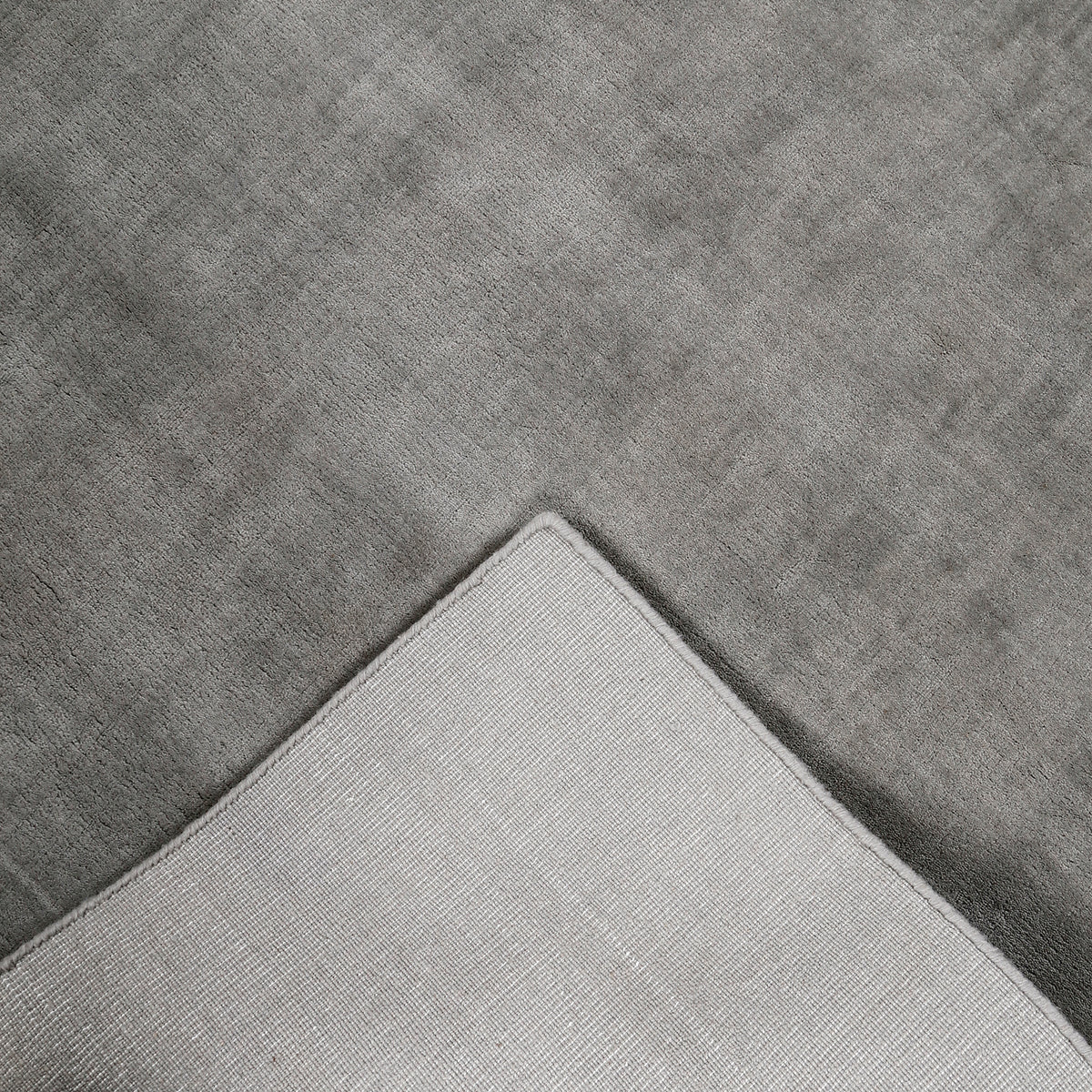 Back detail of grey hand woven Loom Lori wool rug showing its woven underside, finished border and handcrafted construction.