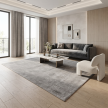 Grey hand woven Loom Lori wool rug styled in a modern living room with a charcoal sofa, marble coffee table, light wooden flooring and neutral décor.