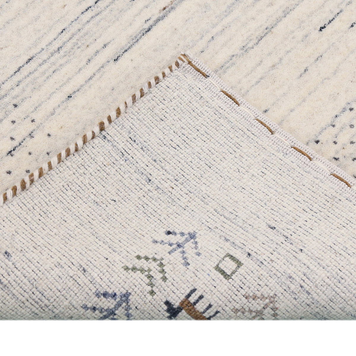 Corner and edge detail of ivory blue-grey Loom Lori wool rug showing dotted border, folk motifs and handcrafted finishing