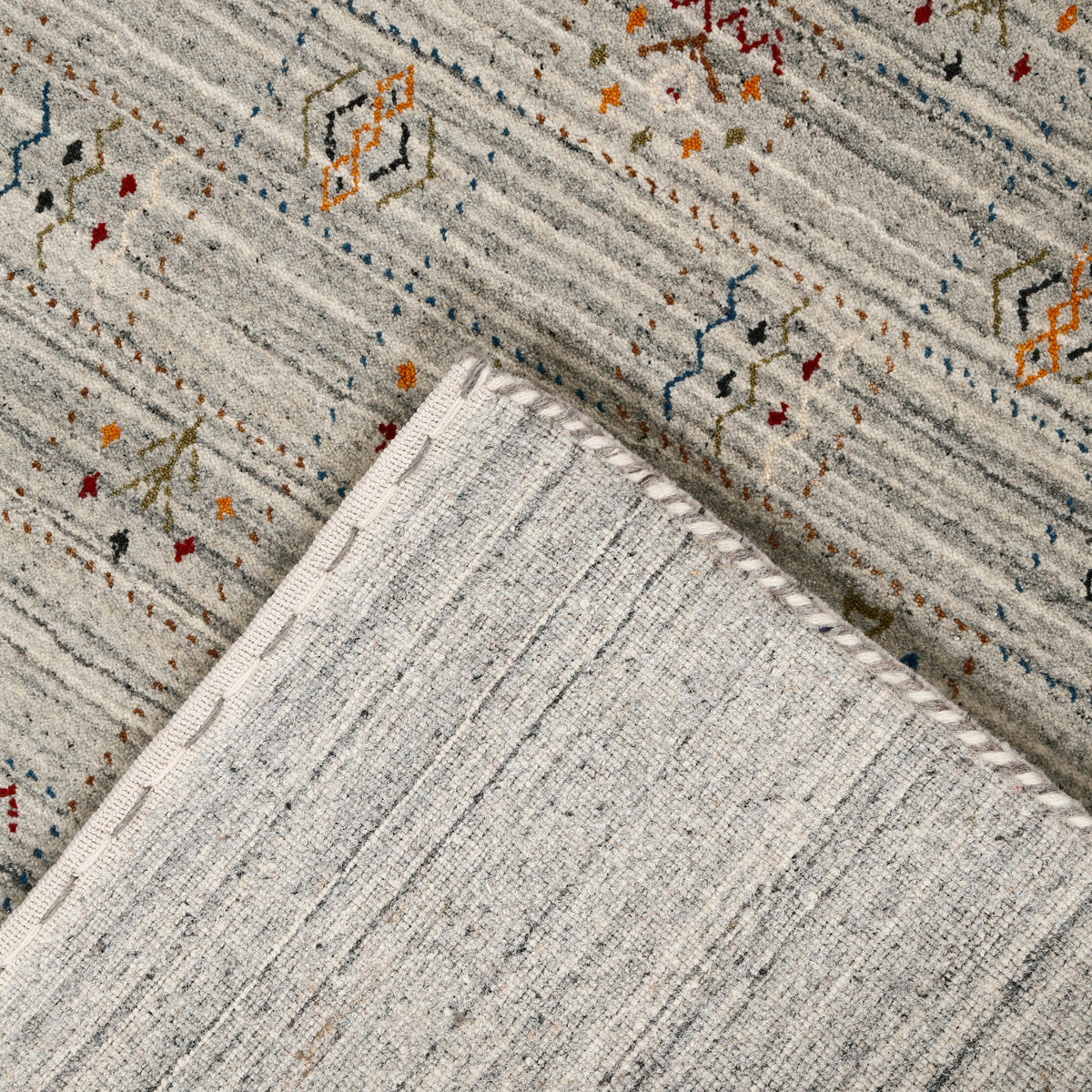 Corner and edge detail of ivory grey Hand Woven Loom Lori wool rug showing natural striations and handcrafted finishing