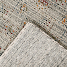 Corner and edge detail of ivory grey Hand Woven Loom Lori wool rug showing natural striations and handcrafted finishing