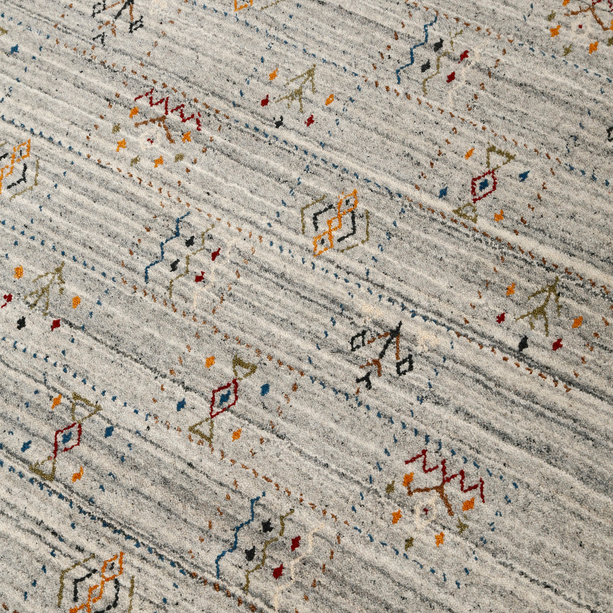 Close-up of ivory grey Hand Woven Loom Lori wool rug showing charcoal striations, colourful tribal motifs and natural wool texture