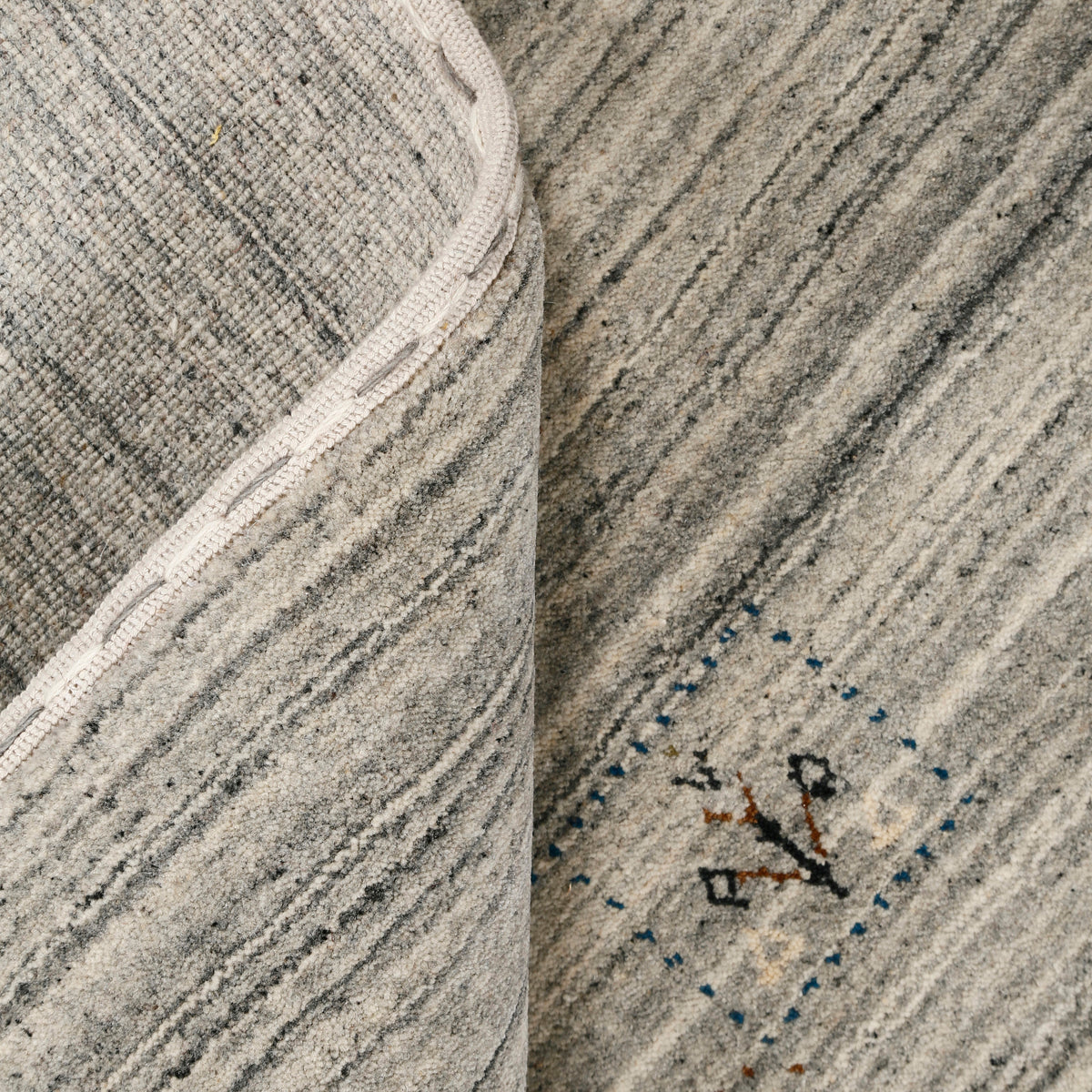 Close-up of ivory grey Hand Woven Loom Lori wool rug showing charcoal striations, colourful tribal motifs and natural wool texture