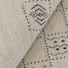 Close-up of ivory beige Hand Woven Loom Lori wool rug showing dotted grid panels, geometric symbols and natural wool texture
