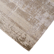 Hand-finished edge and softly distressed neutral surface of the Ivory Haze hand knotted modern rug