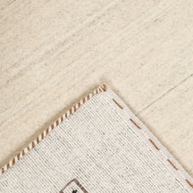 Corner and edge detail of ivory Loom Lori wool rug showing geometric motifs and traditional handcrafted finishing