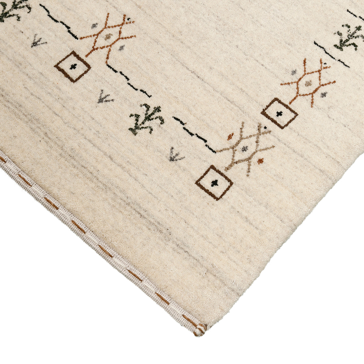 Corner and edge detail of ivory Loom Lori wool rug showing geometric motifs and traditional handcrafted finishing