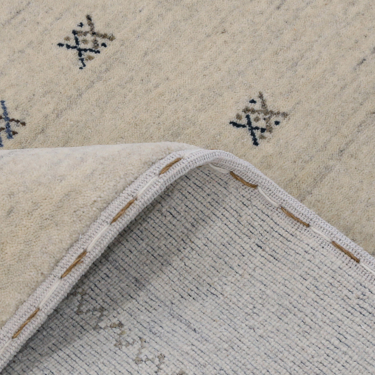 Close-up of ivory Hand Woven Loom Lori wool rug showing natural wool texture, grey striations and small geometric tribal motifs