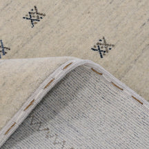Close-up of ivory Hand Woven Loom Lori wool rug showing natural wool texture, grey striations and small geometric tribal motifs