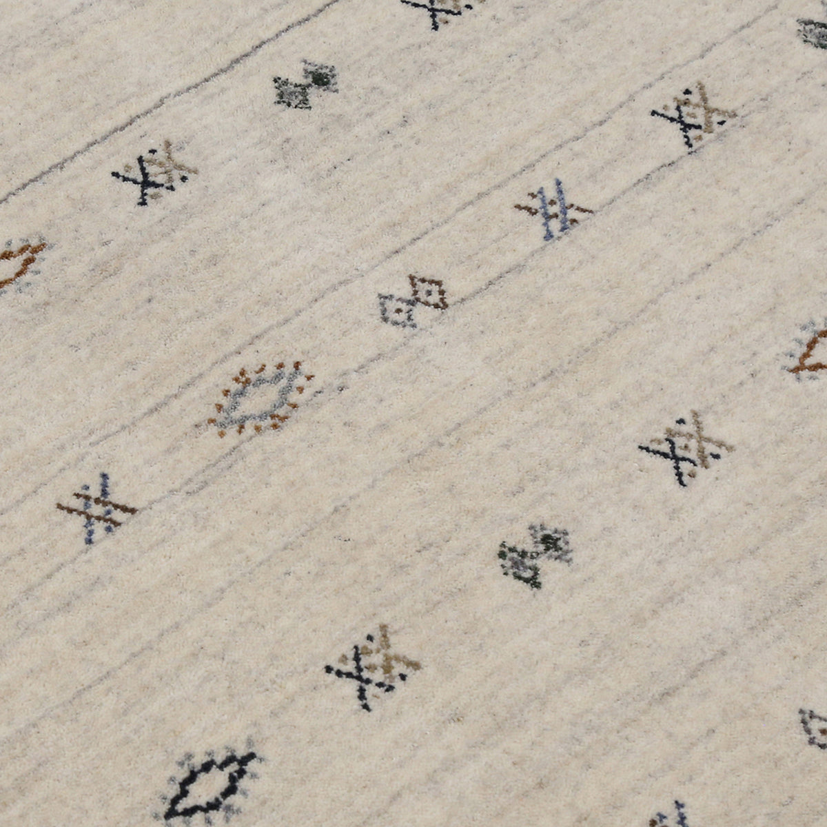 Close-up of ivory Hand Woven Loom Lori wool rug showing natural wool texture, grey striations and small geometric tribal motifs