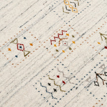 Close-up of ivory cream Hand Woven Loom Lori wool rug showing grey-blue striations, dotted panels and colourful tribal motifs
