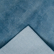 Back and edge detail of light blue hand woven Loom Lori wool rug showing its woven construction, finished border and handcrafted structure.