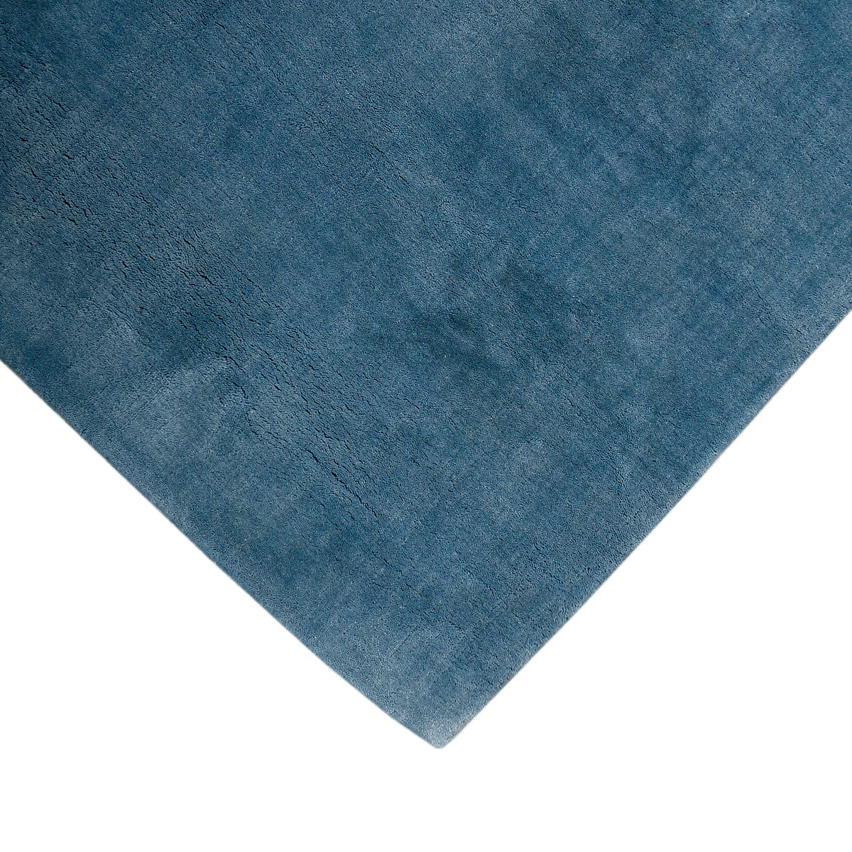 Corner and edge detail of light blue hand woven Loom Lori wool rug showing its neat finishing, soft texture and plush 12-15 mm pile.
