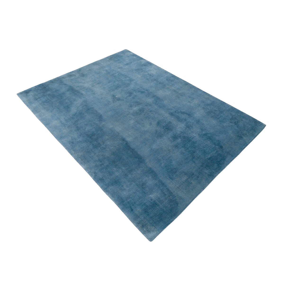 Side angle view of light blue hand woven Loom Lori wool rug showing its rectangular shape, soft surface and subtle tonal texture.