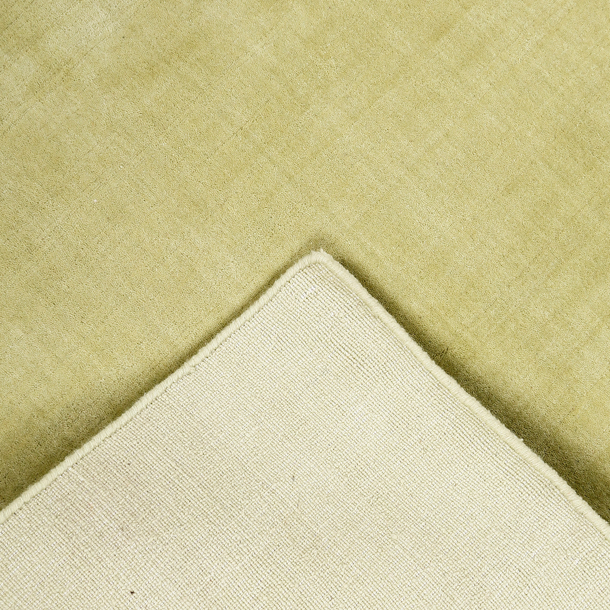 Back and edge detail of light green hand woven Loom Lori wool rug showing its woven construction, finished border and handcrafted structure.