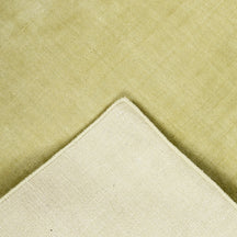 Back and edge detail of light green hand woven Loom Lori wool rug showing its woven construction, finished border and handcrafted structure.