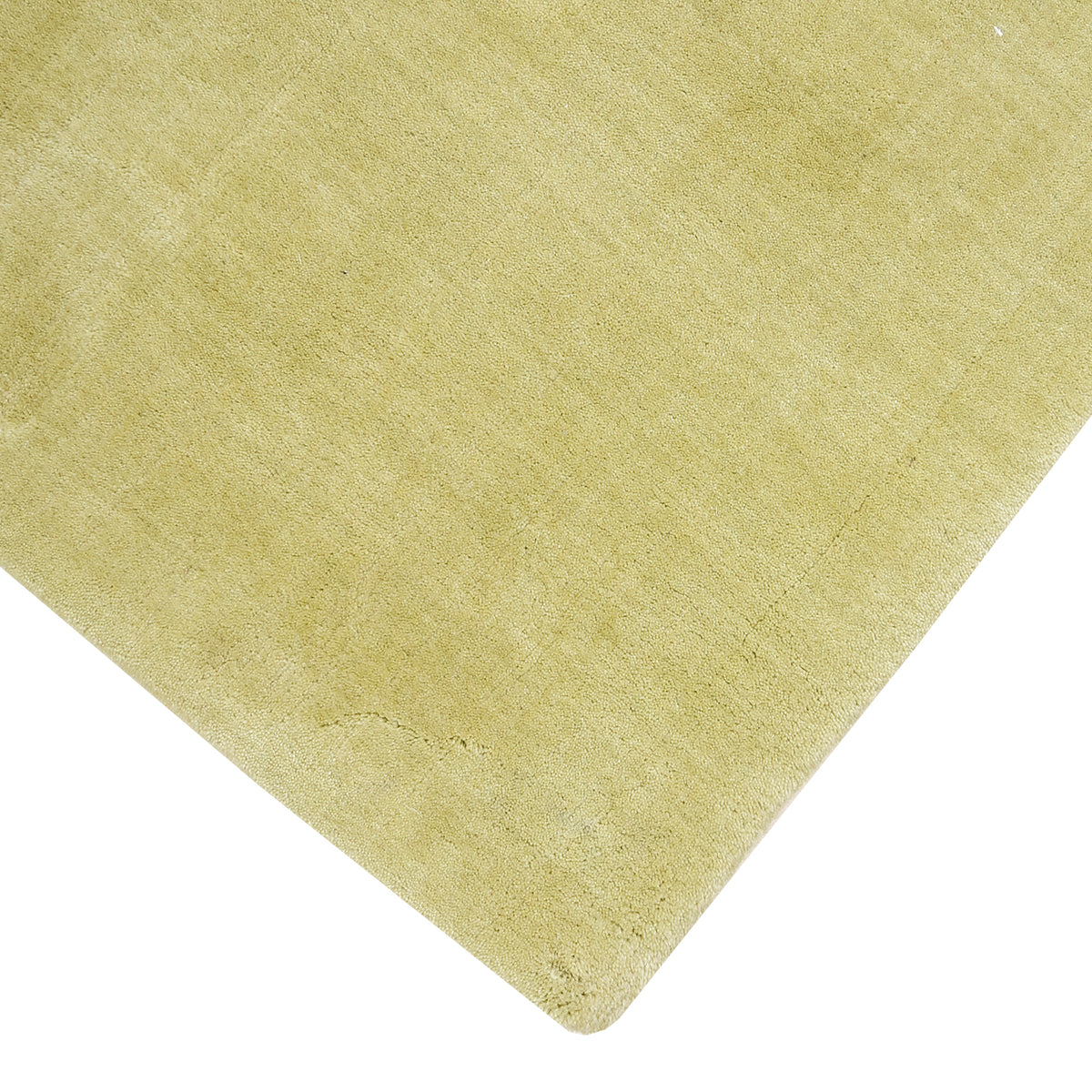 Close view of the corner and edge of light green Loom Lori wool rug showing its neat finishing, soft texture and 12-15 mm pile.