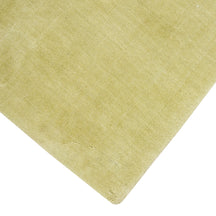 Close view of the corner and edge of light green Loom Lori wool rug showing its neat finishing, soft texture and 12-15 mm pile.