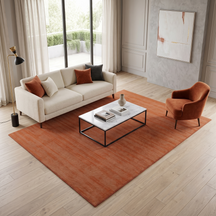 Light pink hand woven Loom Lori wool rug styled in a modern living room with a cream sofa, warm accent chair, marble coffee table and wooden flooring.