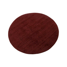 Angled view of Maroon Hand Woven Loom Lori round wool rug showing the round silhouette and subtle tonal woven texture.