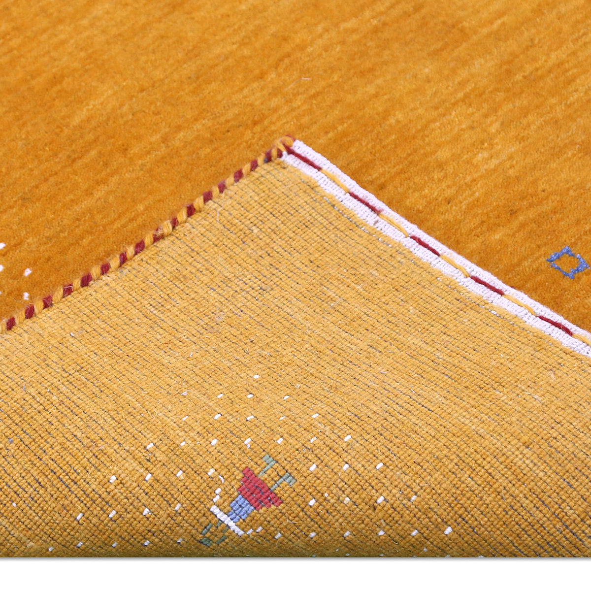 Corner and edge detail of golden mustard Loom Lori wool rug showing ivory dotted sections, folk motifs and handcrafted finishing