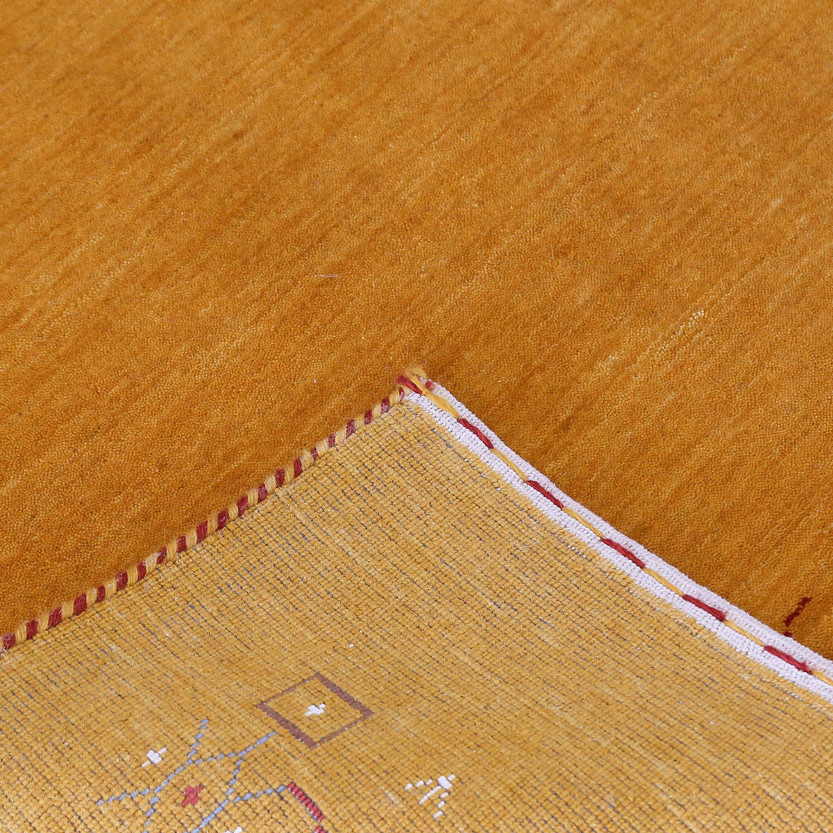 Corner and edge detail of golden mustard Loom Lori wool rug showing geometric tribal motifs and handcrafted finishing