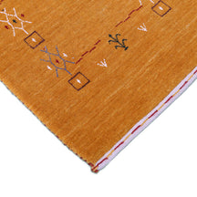Corner and edge detail of golden mustard Loom Lori wool rug showing geometric tribal motifs and handcrafted finishing