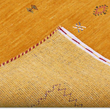Corner and edge detail of golden mustard Loom Lori wool rug showing dark zigzag border and traditional handcrafted finishing