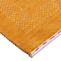 Corner and edge detail of mustard yellow Hand Woven Loom Lori wool rug showing dotted geometric border and handcrafted finishing