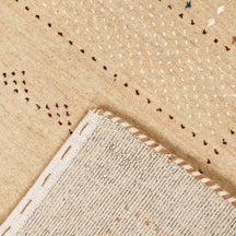 Corner and edge detail of natural beige Loom Lori wool rug showing delicate dotted border and traditional handcrafted finishing