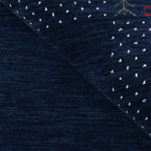 Close-up of navy blue Hand Woven Loom Lori wool rug showing natural wool texture, botanical symbols and colourful tribal motifs