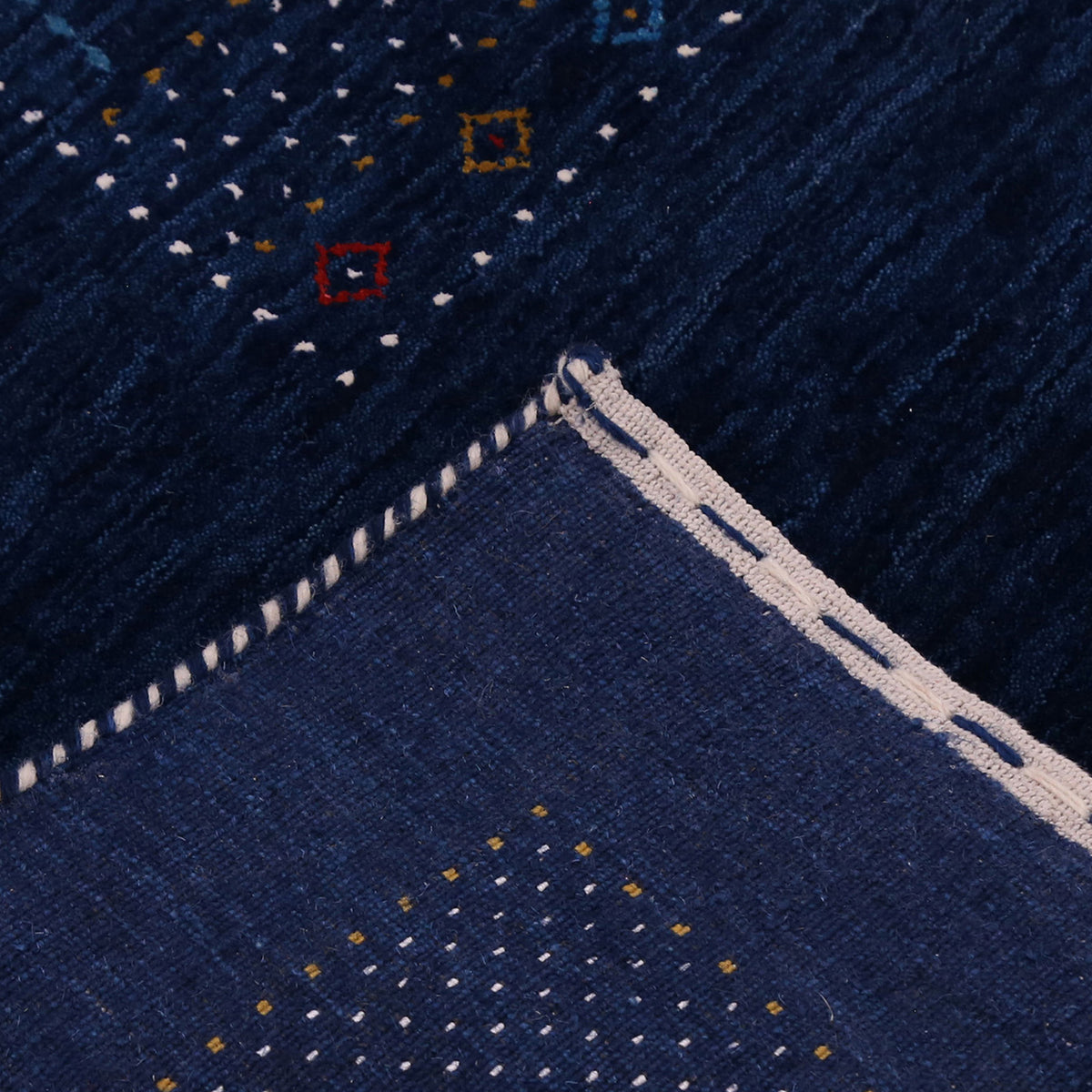 Corner and edge detail of navy blue Hand Woven Loom Lori wool rug showing dotted geometric border and handcrafted finishing