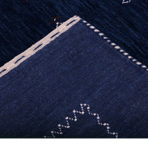 Corner and edge detail of navy blue Loom Lori wool rug showing contrasting ivory zigzag border and handcrafted finishing