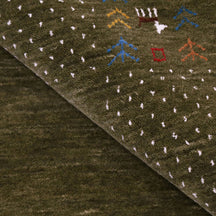Close-up of olive green Hand Woven Loom Lori wool rug showing natural wool texture, botanical symbols and colourful tribal motifs