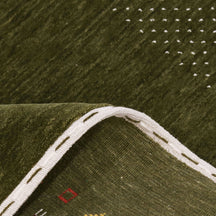Close-up of olive green Hand Woven Loom Lori wool rug showing natural wool texture, botanical symbols and colourful tribal motifs