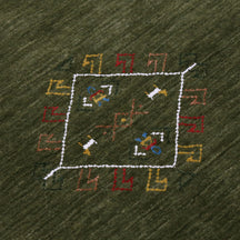 Close-up of olive green Hand Woven Loom Lori wool rug showing central diamond motif, colourful folk details and natural wool texture
