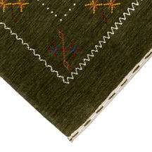 Corner and edge detail of olive green Hand Woven Loom Lori wool rug showing zigzag geometric border and handcrafted finishing