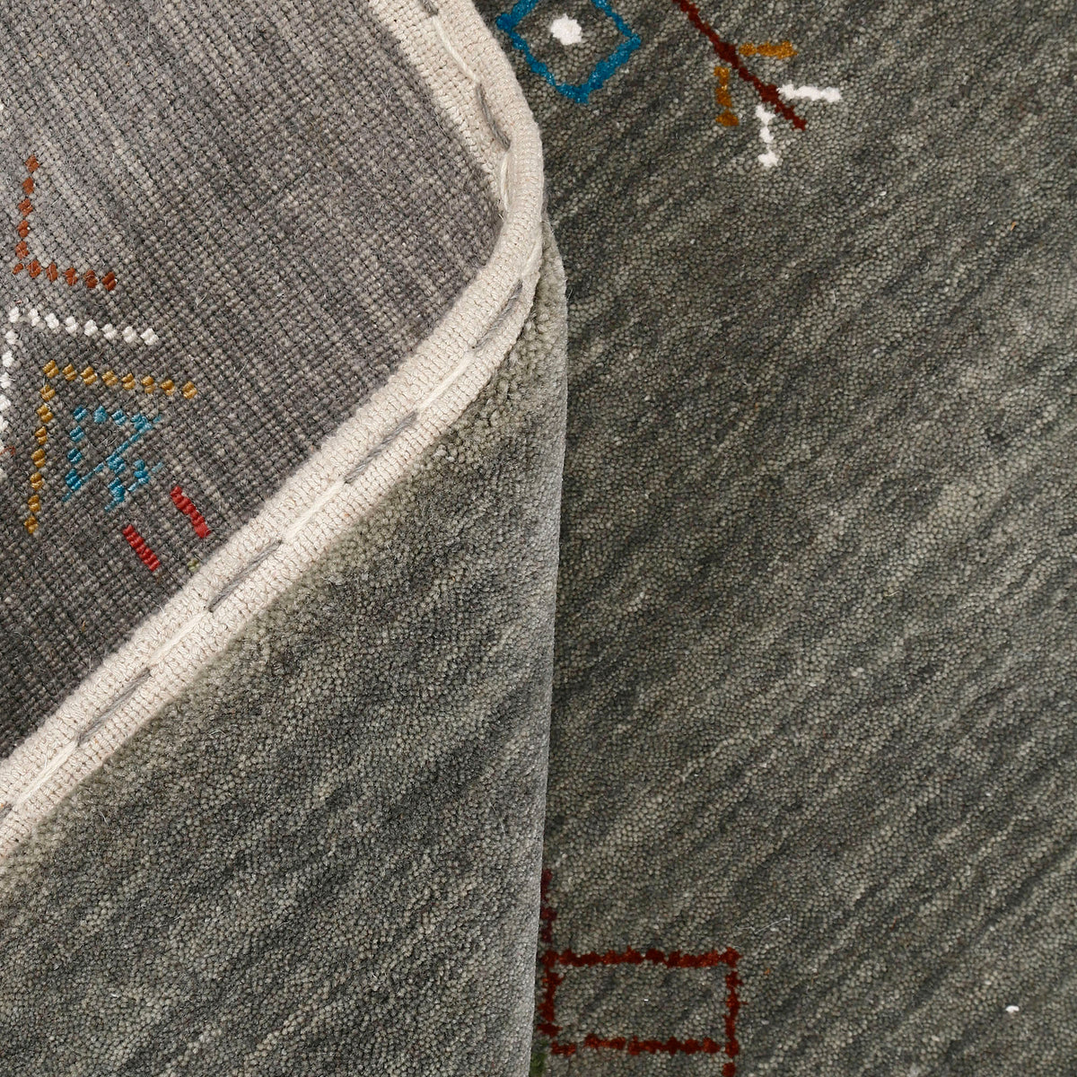 Close-up of olive grey Hand Woven Loom Lori wool rug showing natural wool texture, diamond detailing and multicolour tribal motifs