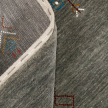 Close-up of olive grey Hand Woven Loom Lori wool rug showing natural wool texture, diamond detailing and multicolour tribal motifs