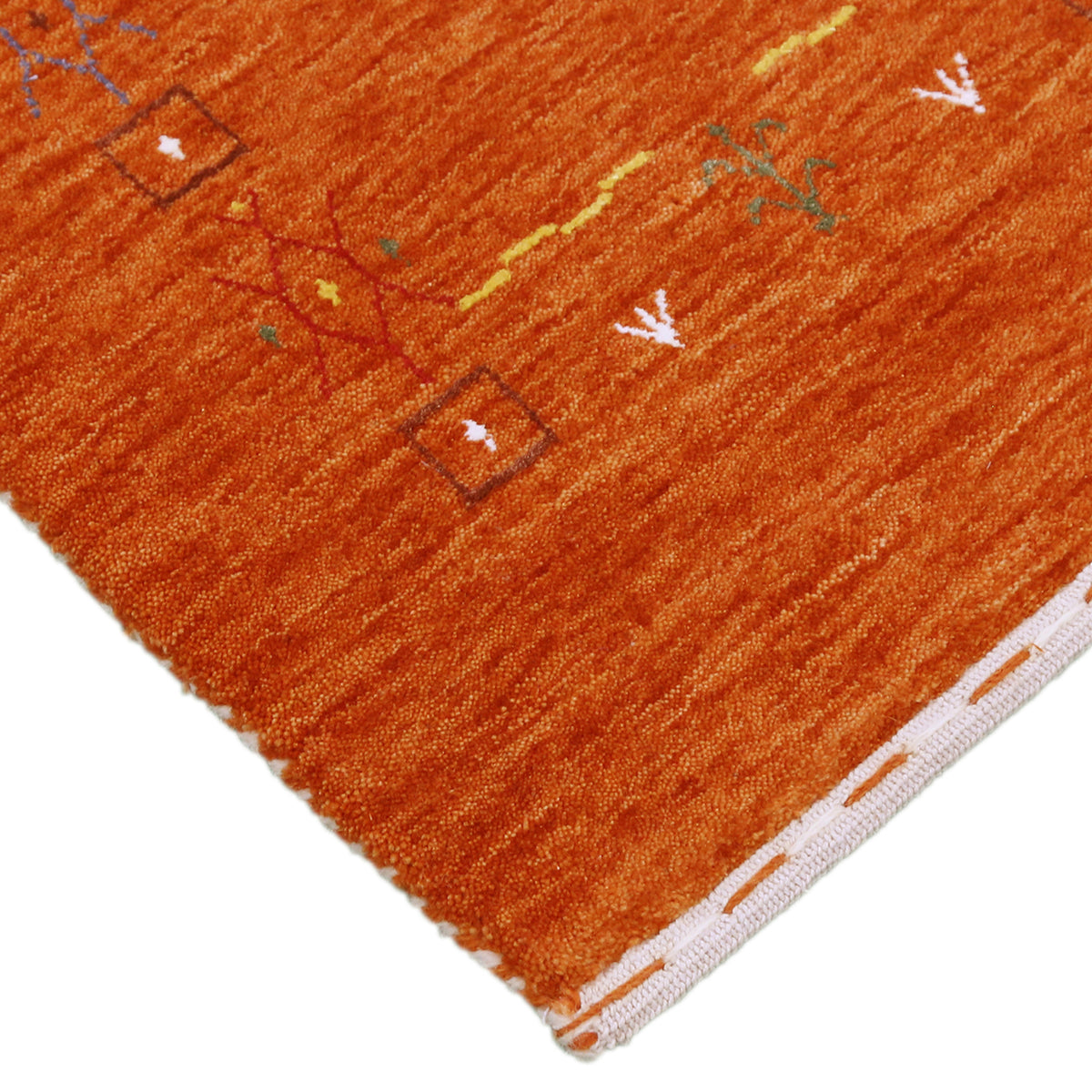 Corner and edge detail of burnt orange Loom Lori wool rug showing symbolic tribal motifs and handcrafted finishing