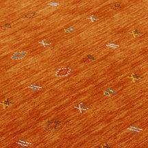 Close-up of terracotta orange Hand Woven Loom Lori wool rug showing natural wool texture and multicolour geometric motifs