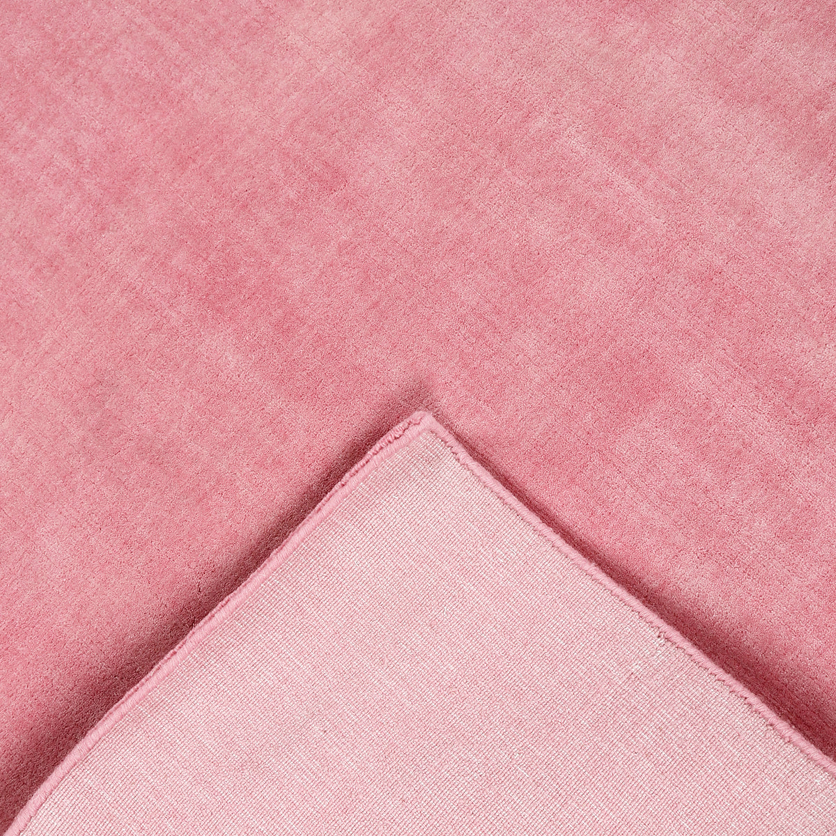Back and edge detail of pink hand woven Loom Lori wool rug showing its woven construction, finished border and handcrafted structure.