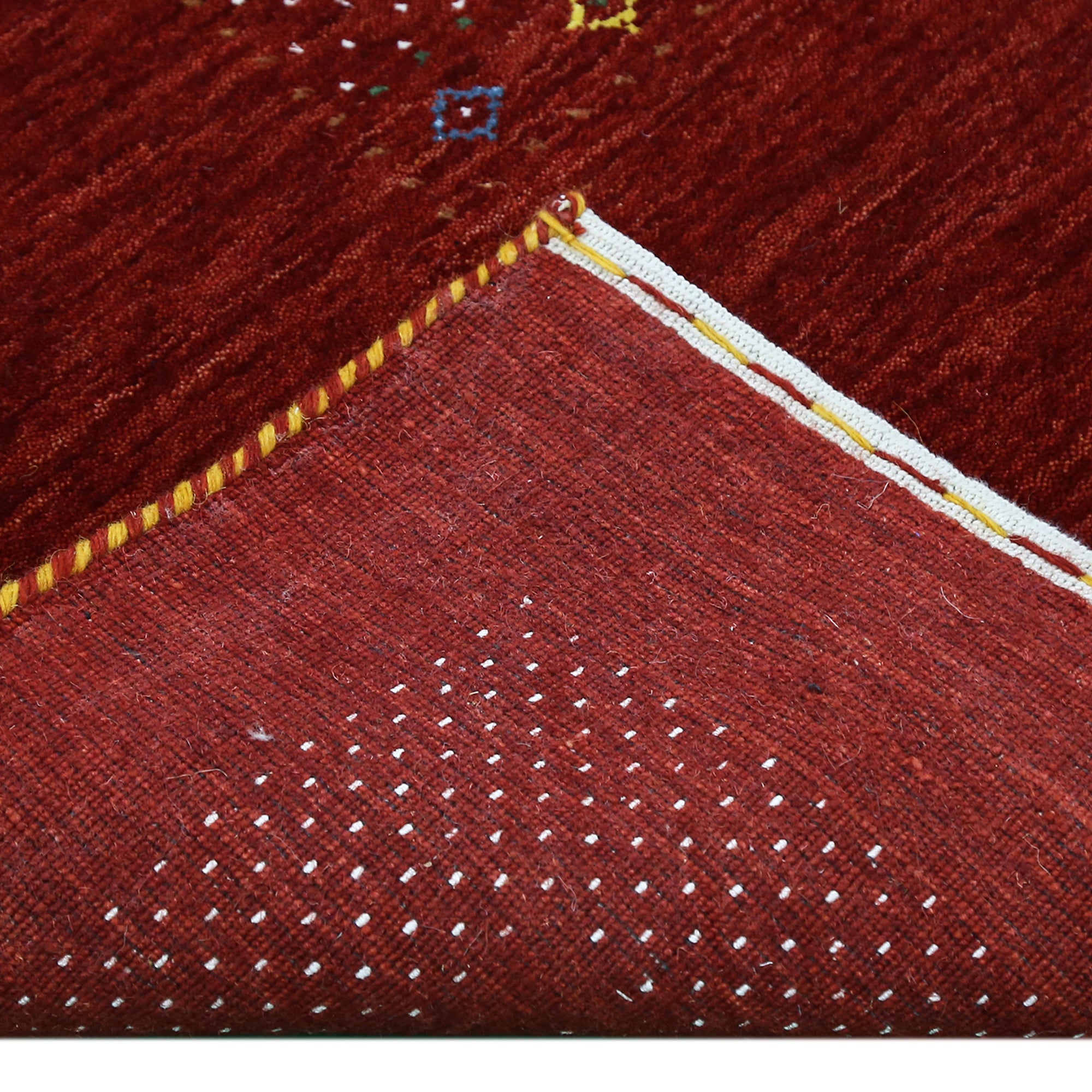 Corner and edge detail of red Hand Woven Loom Lori wool rug showing dotted border and handcrafted finishing