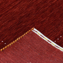 Corner and edge detail of red Hand Woven Loom Lori wool rug showing zigzag geometric border and handcrafted finishing