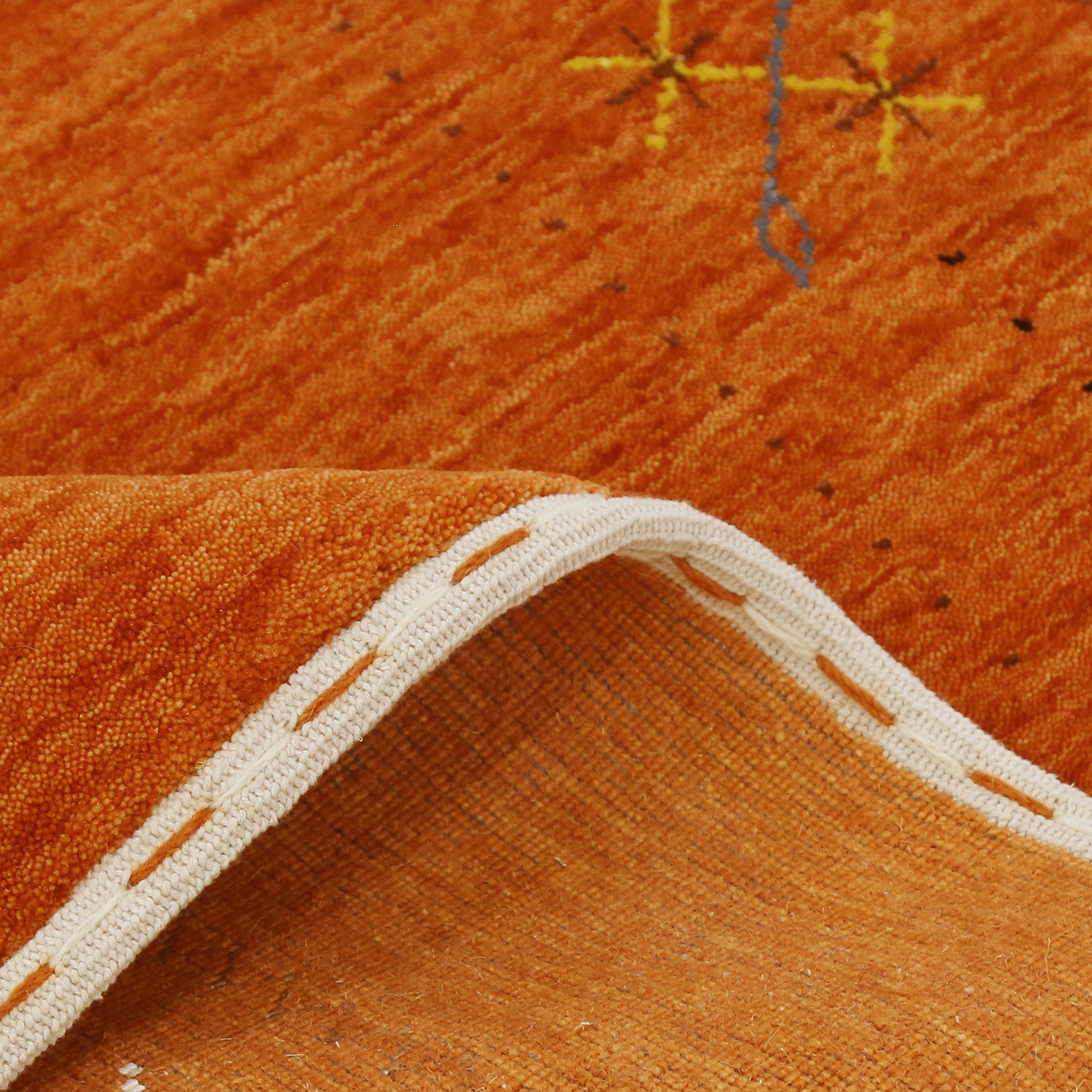 Close-up texture of rust orange Hand Woven Loom Lori wool rug showing natural wool fibres and delicate floral motif detailing