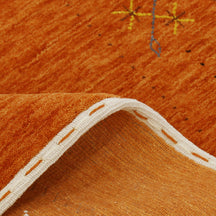 Close-up texture of rust orange Hand Woven Loom Lori wool rug showing natural wool fibres and delicate floral motif detailing