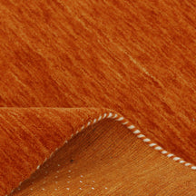 Close-up of terracotta orange Hand Woven Loom Lori wool rug showing natural wool texture, dotted detailing and multicolour tribal motifs