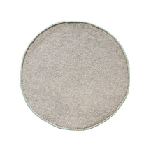 Side angle view of sage green round hand tufted wool smiley face kids rug showcasing its plush pile, circular shape and playful design.