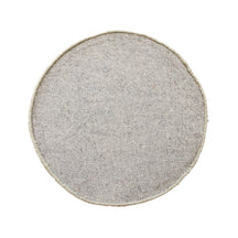 Side angle view of taupe smiley face wool kids rug showing its plush hand tufted pile, round shape and playful cartoon design.