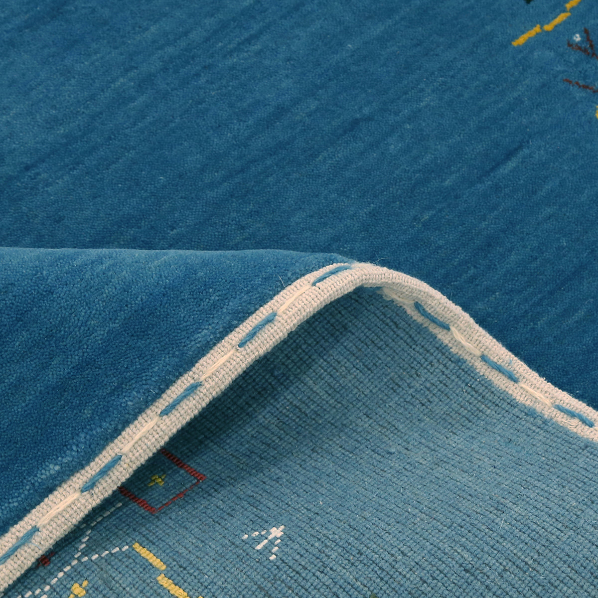 Close-up of teal blue Hand Woven Loom Lori wool rug showing natural wool texture and detailed symbolic tribal motifs